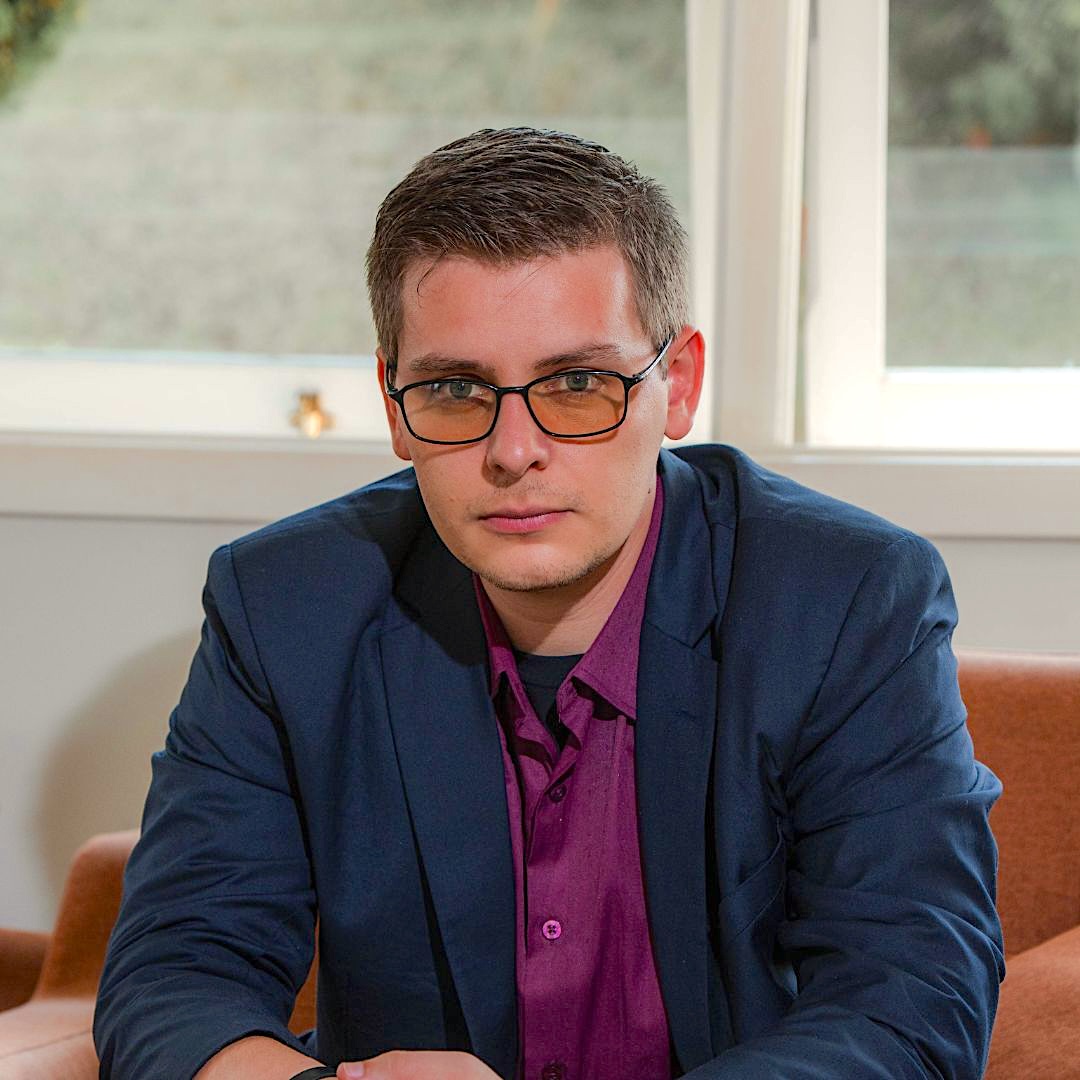 Giovane Carlos - Retrato profissional, blazer azul marinho e camisa roxa, poltrona cobre